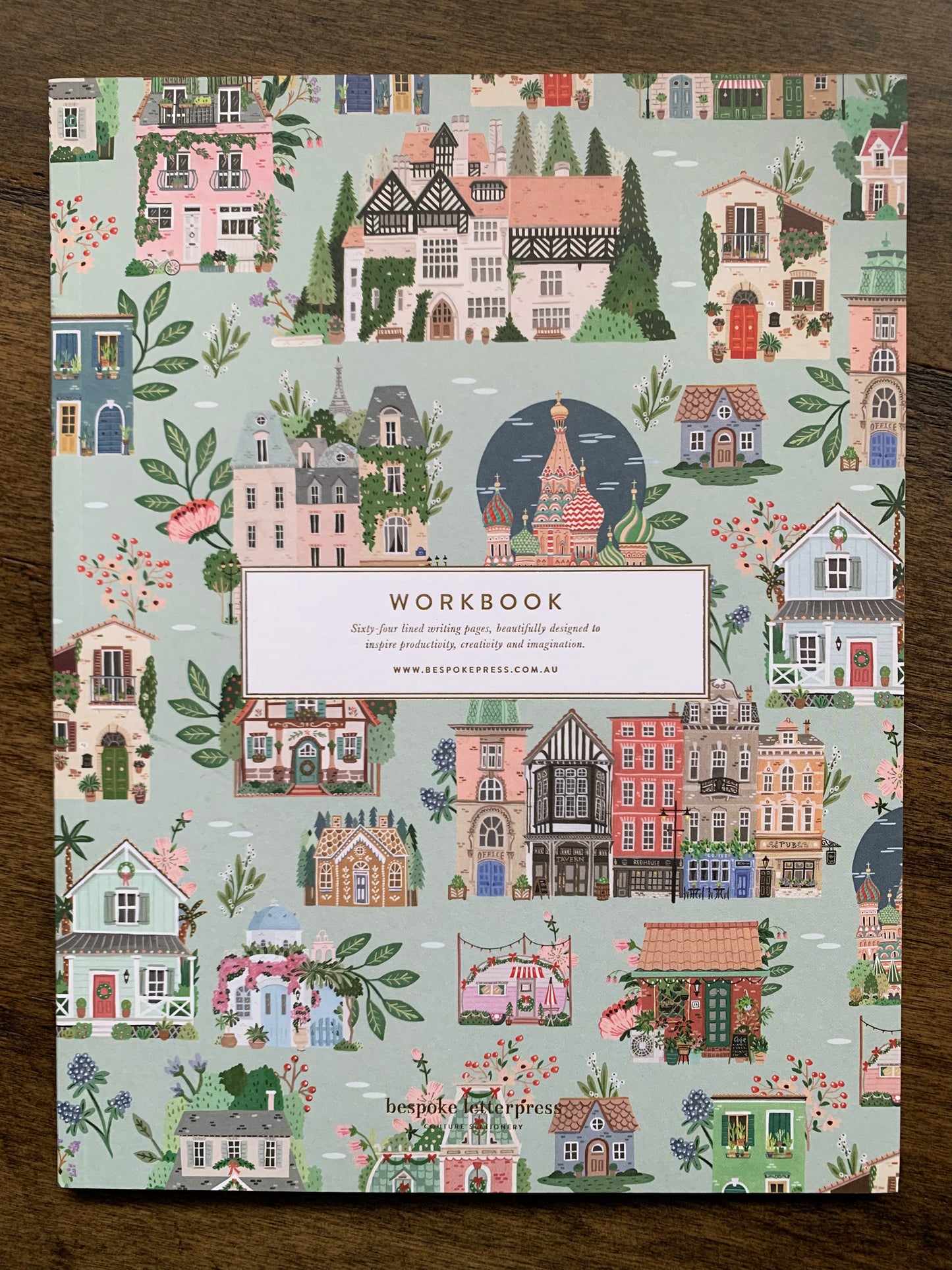 Around the world lined workbook 64 pages whimsical buildings caravans salmon pink tones on pale green background