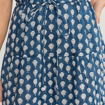 Close-up of a blue dress with a white repeating floral or leaf block-print pattern and a matching drawstring waist.